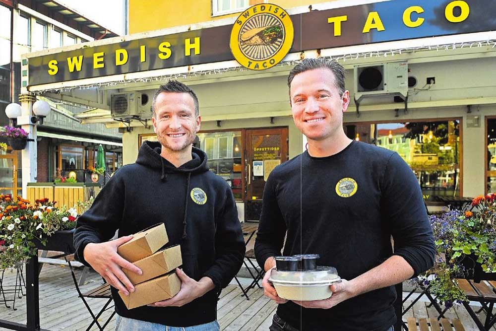 Två män håller i takeaway utanför Swedish taco